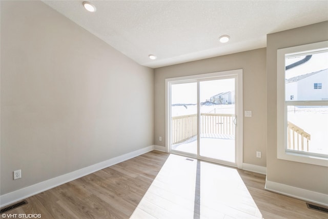 spare room featuring a textured ceiling, light wood-style floors, visible vents, and baseboards