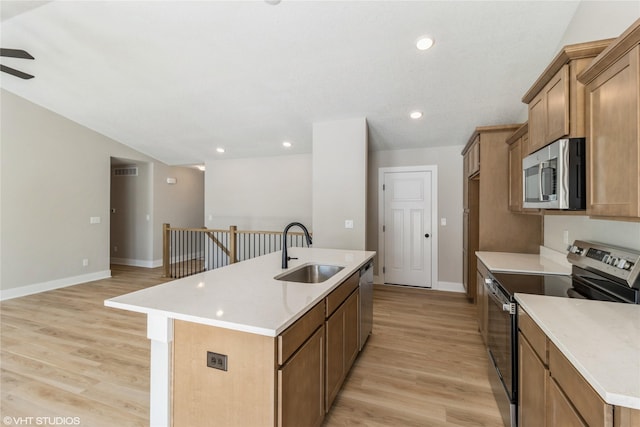 kitchen with recessed lighting, a sink, appliances with stainless steel finishes, light wood finished floors, and an island with sink