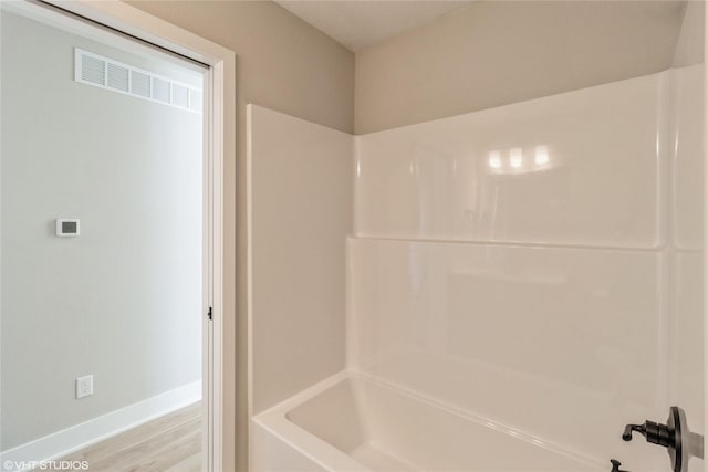 bathroom with shower / bath combination, wood finished floors, visible vents, and baseboards