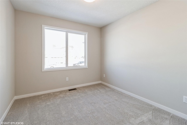 carpeted empty room featuring visible vents and baseboards