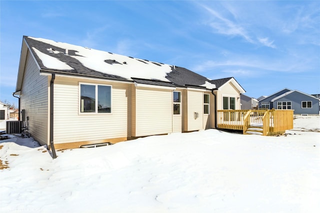 snow covered house with cooling unit and a wooden deck