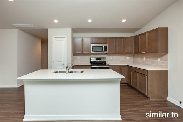 kitchen with dark hardwood / wood-style flooring, sink, a center island with sink, and appliances with stainless steel finishes