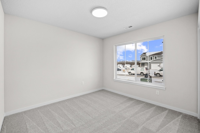 empty room featuring carpet, visible vents, and baseboards