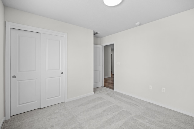 unfurnished bedroom with a closet, light carpet, visible vents, and baseboards