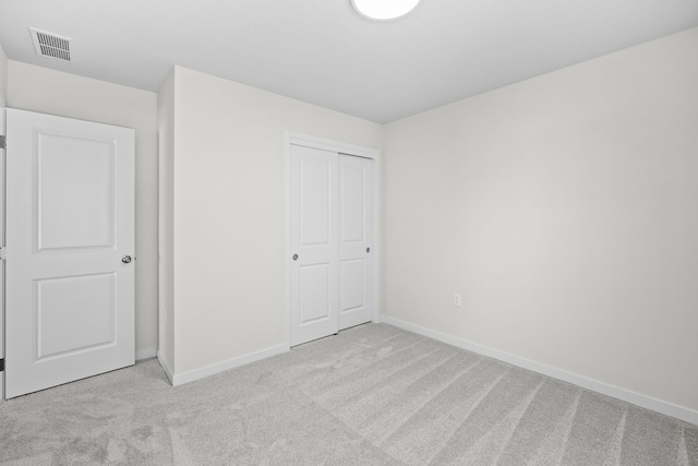 unfurnished bedroom featuring a closet, visible vents, light carpet, and baseboards