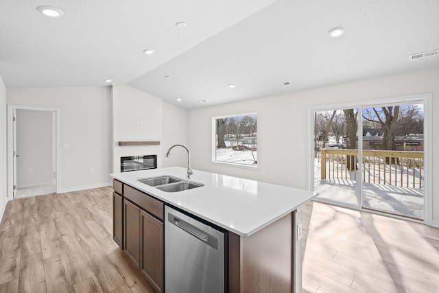 kitchen featuring a sink, visible vents, light countertops, dishwasher, and an island with sink