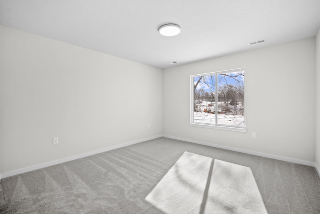 carpeted empty room featuring baseboards and visible vents