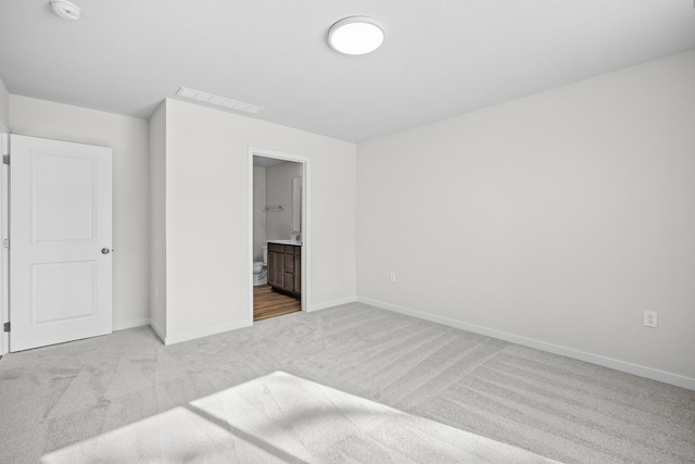 bedroom with light carpet, connected bathroom, visible vents, and baseboards