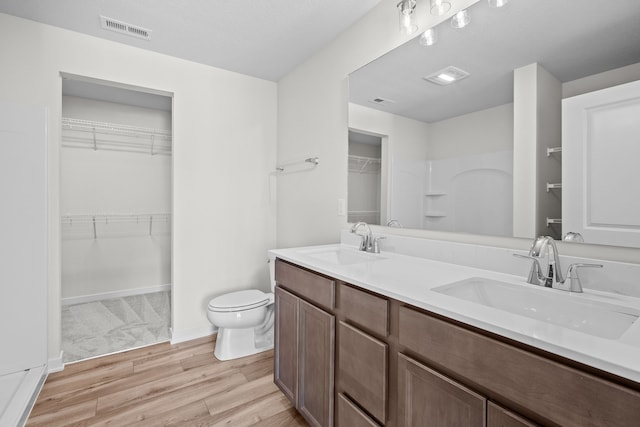 full bath with double vanity, wood finished floors, a sink, and visible vents