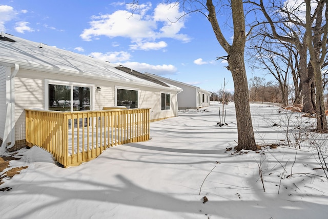 snow covered house featuring a wooden deck