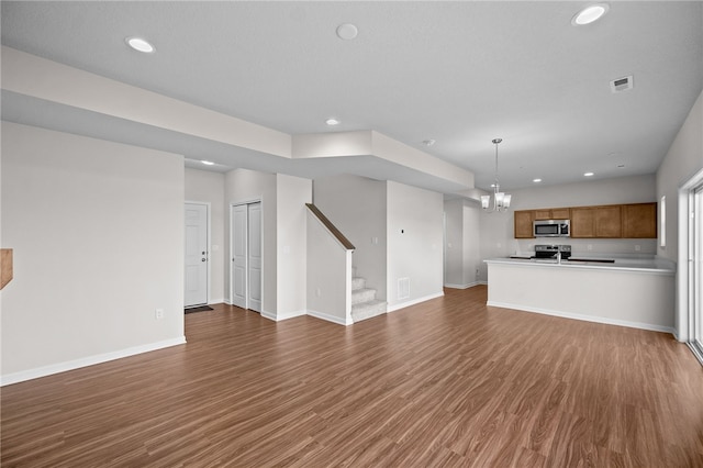 unfurnished living room with an inviting chandelier and dark hardwood / wood-style flooring