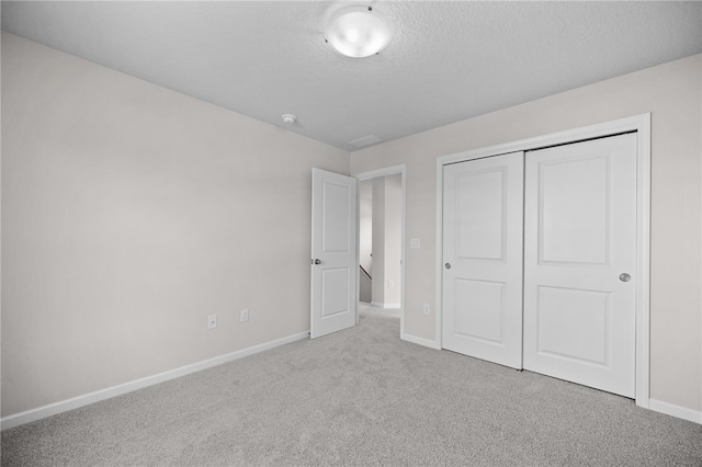 unfurnished bedroom with light carpet, a closet, and a textured ceiling