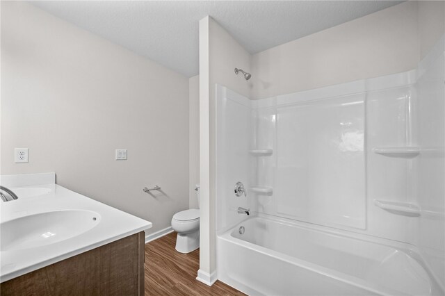 full bathroom with toilet, a textured ceiling, vanity, shower / washtub combination, and hardwood / wood-style flooring