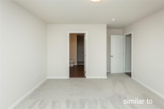 unfurnished bedroom featuring ensuite bath and light colored carpet