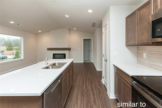 kitchen featuring sink, tasteful backsplash, dark hardwood / wood-style floors, vaulted ceiling, and appliances with stainless steel finishes