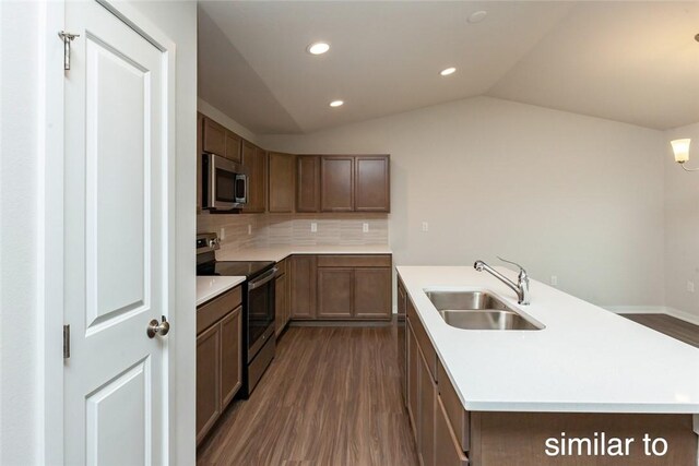 kitchen featuring appliances with stainless steel finishes, vaulted ceiling, dark wood-type flooring, and sink