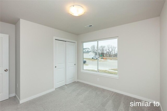 unfurnished bedroom with a closet and light colored carpet