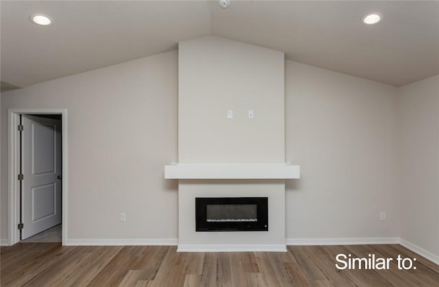 unfurnished living room with lofted ceiling, hardwood / wood-style floors, and a large fireplace