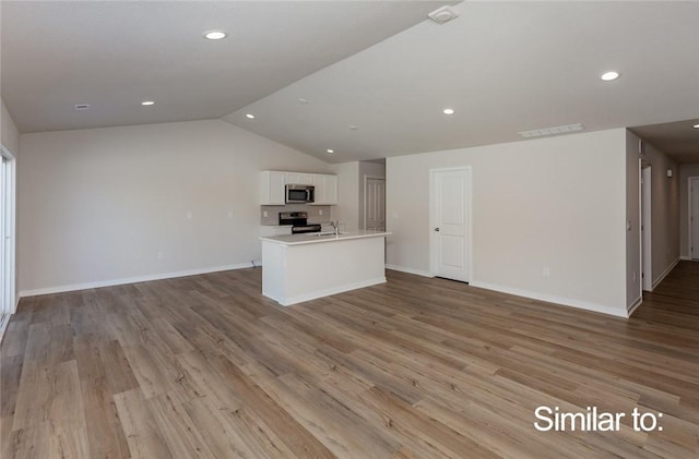 unfurnished living room with lofted ceiling and light wood-type flooring