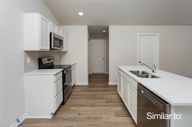 kitchen with sink, white cabinets, decorative backsplash, stainless steel appliances, and light wood-type flooring