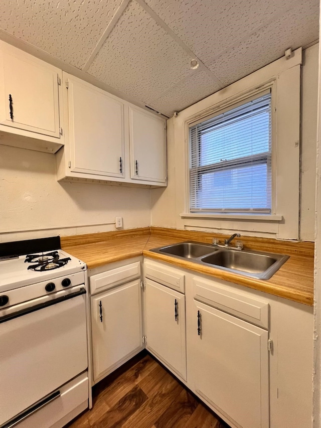 kitchen with sink, a drop ceiling, white range oven, white cabinets, and dark hardwood / wood-style flooring