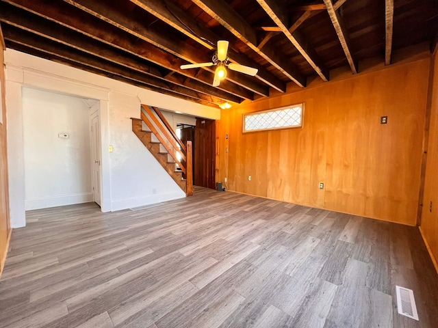 basement with wooden walls, hardwood / wood-style flooring, and ceiling fan