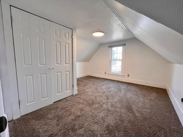 bonus room with lofted ceiling and dark carpet