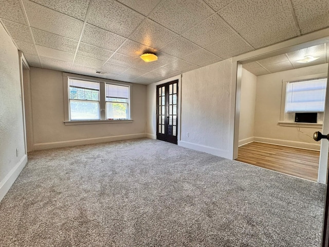 empty room featuring french doors, a wealth of natural light, wood-type flooring, and a paneled ceiling