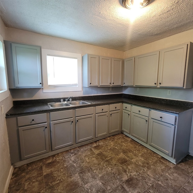 kitchen featuring a textured ceiling, gray cabinets, and sink