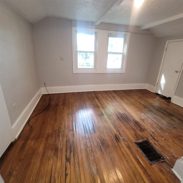 additional living space featuring dark hardwood / wood-style floors, a textured ceiling, and vaulted ceiling