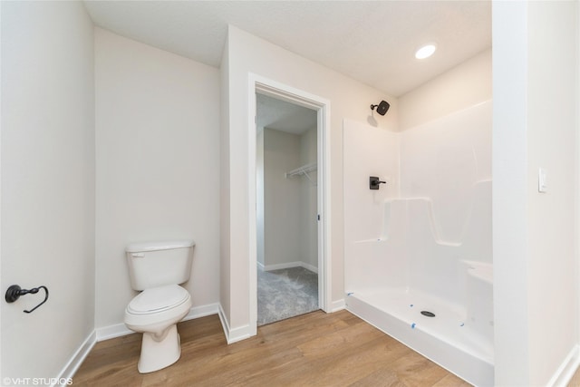 bathroom featuring toilet, baseboards, walk in shower, and wood finished floors