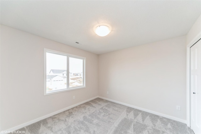 unfurnished room with light carpet, visible vents, and baseboards