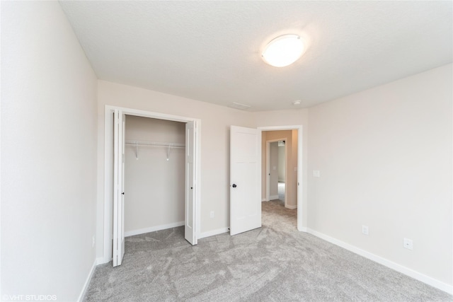 unfurnished bedroom with a textured ceiling, a closet, carpet flooring, and baseboards