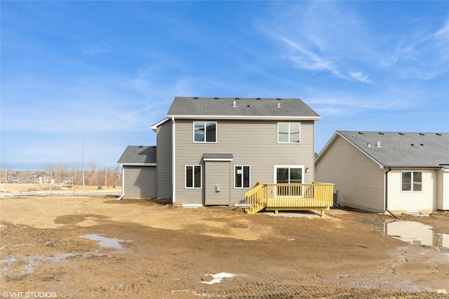 rear view of property featuring roof with shingles and a wooden deck