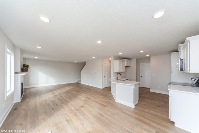 kitchen with a sink, open floor plan, electric stove, light countertops, and light wood finished floors