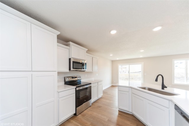 kitchen featuring appliances with stainless steel finishes, a sink, a wealth of natural light, and light wood-style floors