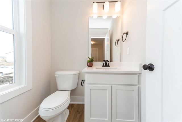 bathroom featuring toilet, vanity, a wealth of natural light, and baseboards