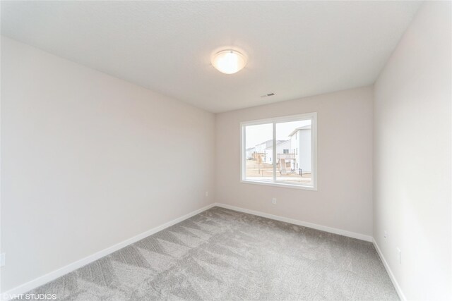 unfurnished room with light colored carpet and baseboards