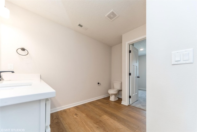 bathroom featuring visible vents, a sink, toilet, and wood finished floors