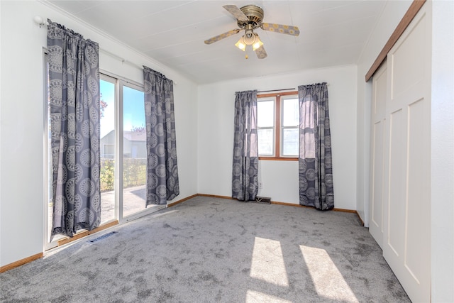 unfurnished bedroom with multiple windows, light carpet, ceiling fan, and crown molding