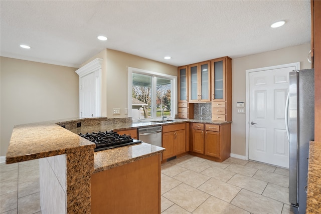 kitchen with stainless steel appliances, light stone counters, kitchen peninsula, a textured ceiling, and sink