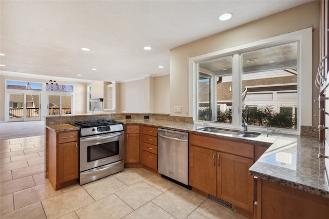 kitchen with stainless steel appliances, kitchen peninsula, a notable chandelier, sink, and dark stone countertops