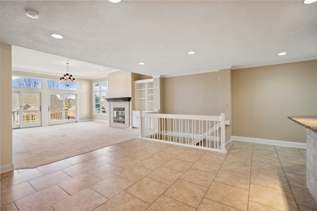 unfurnished living room featuring an inviting chandelier, light colored carpet, ornamental molding, and a textured ceiling