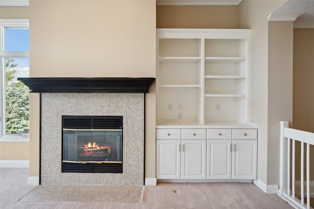 room details featuring built in features, a fireplace, carpet floors, and crown molding