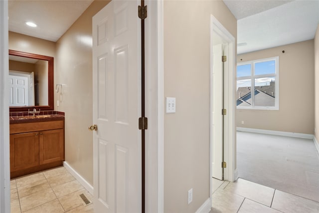 corridor featuring light colored carpet and sink