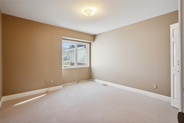 carpeted empty room featuring a textured ceiling