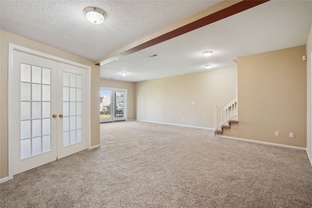 empty room with french doors, a textured ceiling, and carpet floors