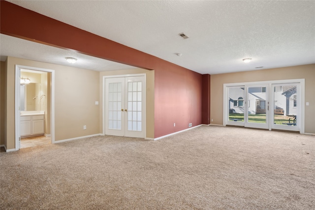 carpeted spare room with a textured ceiling and french doors