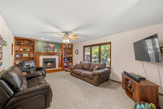 living room featuring a tiled fireplace, light carpet, and ceiling fan