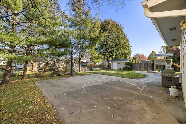 view of patio featuring a storage unit and basketball hoop